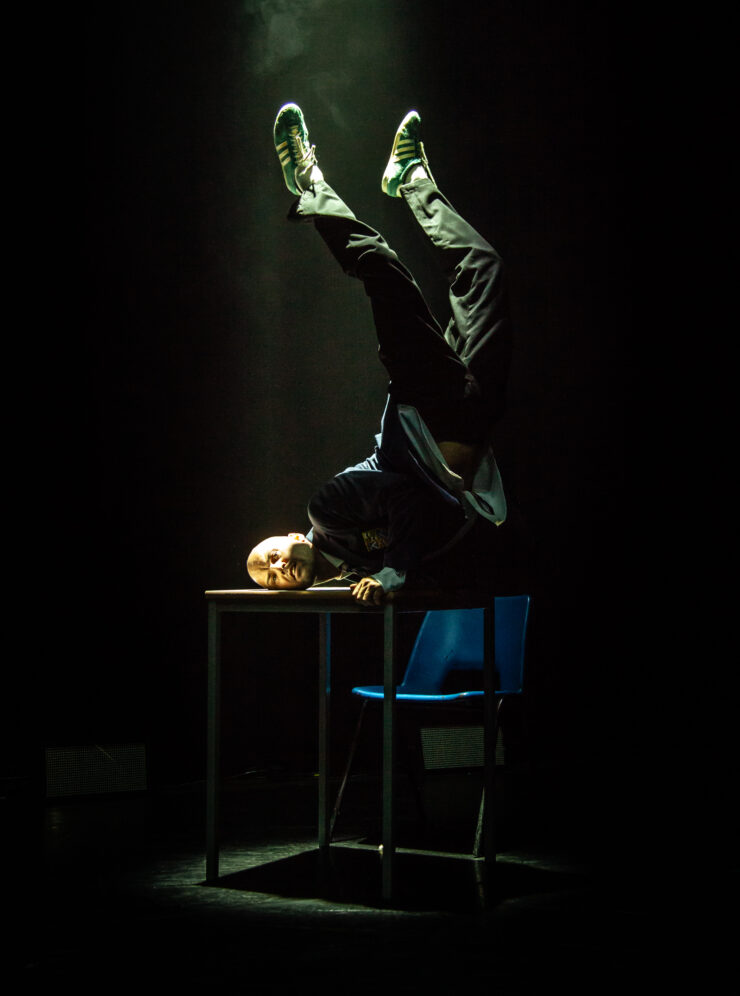 Male dancer standing on his arms on top of a desk