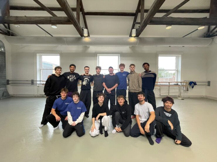 A group of young dancers, some standing, some sitting with Gary Clarke in the middle of the group